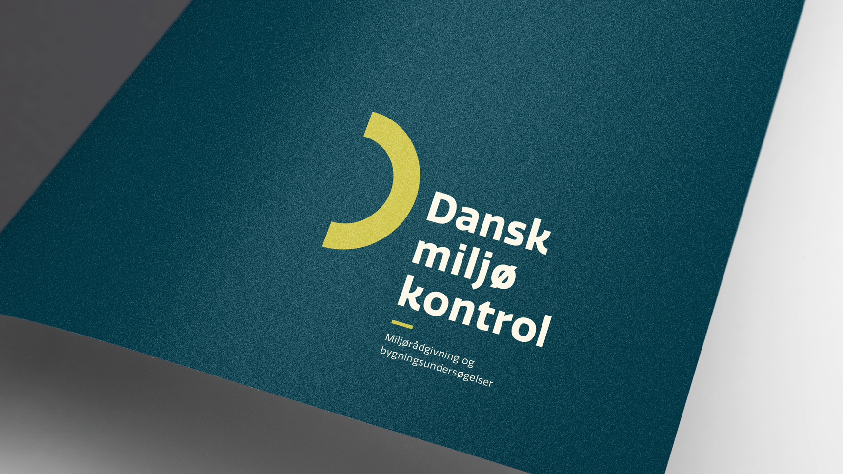 Et mockup af en mappe i mørk blålig farve med logoet for Dansk Miljøkontrol på